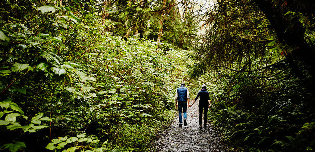 Couple walking through dense forest trail