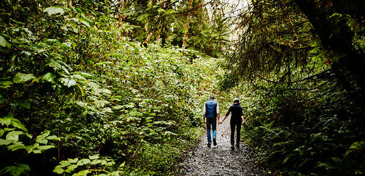 Couple walking through dense forest trail