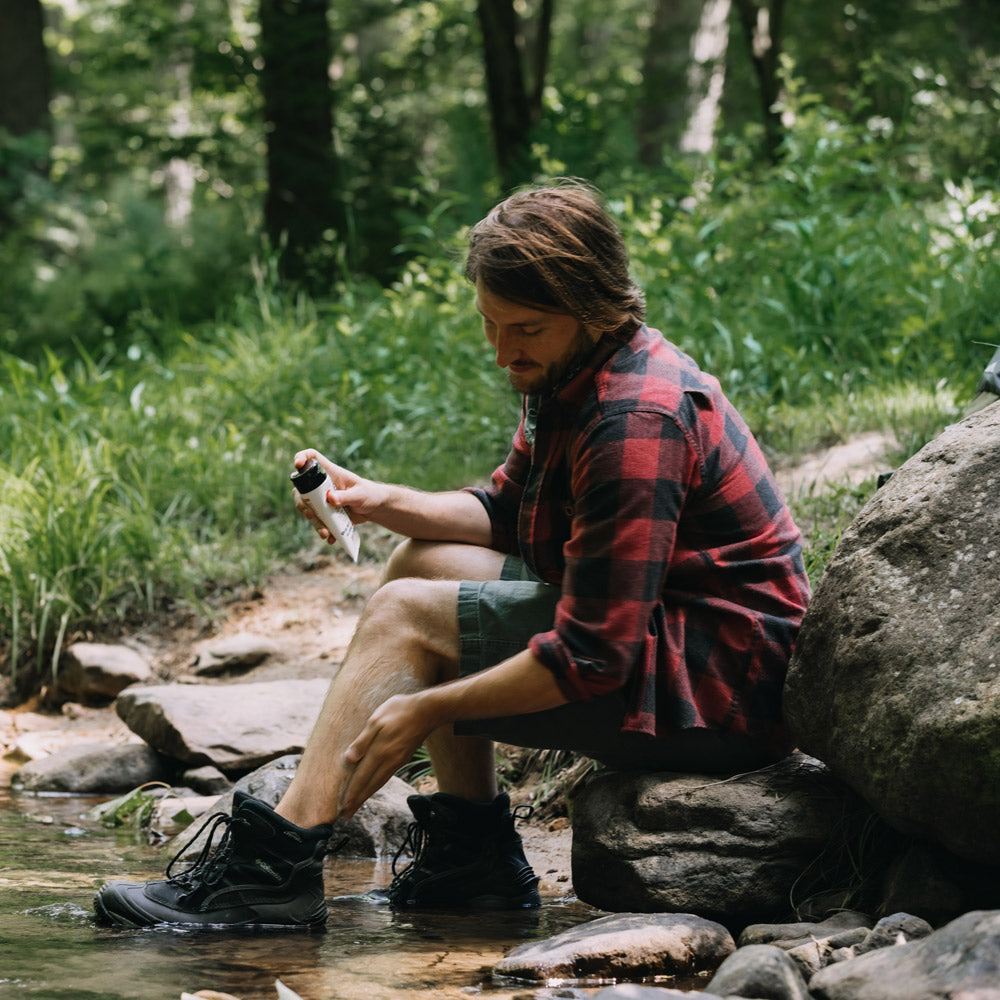 Man washing leg with Tecnu Extreme in a river