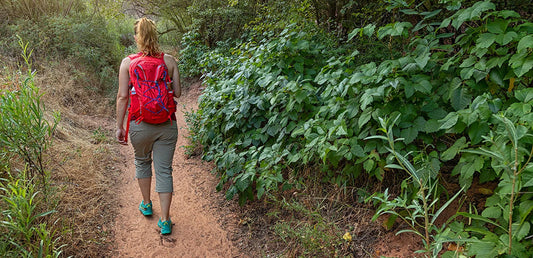 woman with backpack hiking on nature trail