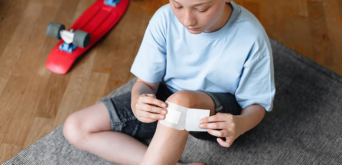 boy applying bandage to his knee