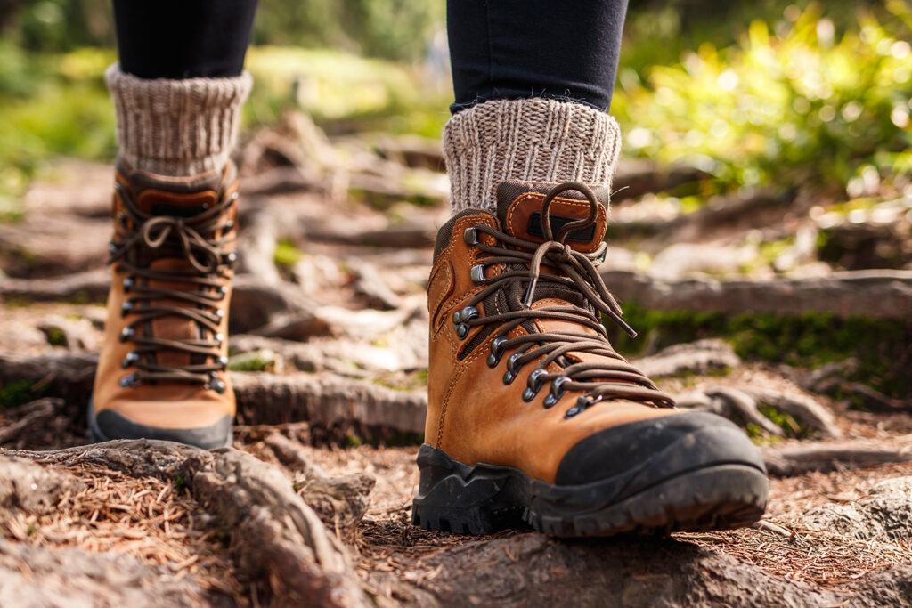 The image shows feet of a hiker wearing brown boots and thick socks to avoid blisters.